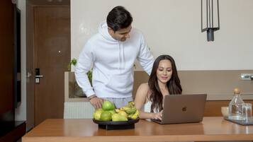 Un'area pranzo moderna con un tavolo in legno, un laptop e una ciotola di mele verdi.