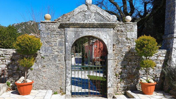A stone archway with a decorative top, flanked by potted plants. - Galini Vines House Authentic Corfu Village Life Wifi A C (Corfu)