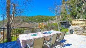 An outdoor dining area with a table set for two, surrounded by metal chairs, overlooking a scenic landscape with hills and a clear blue sky. - Galini Vines House Authentic Corfu Village Life Wifi A C (Corfu)