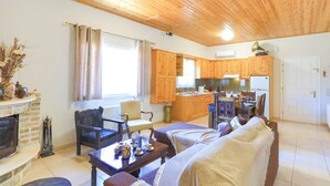 A cozy living room with a fireplace, a dining area, and a kitchen with wooden cabinets. - Galini Vines House Authentic Corfu Village Life Wifi A C (Corfu)