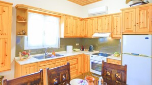 A kitchen with wooden cabinets, a sink, a stove, and a refrigerator. - Galini Vines House Authentic Corfu Village Life Wifi A C (Corfu)