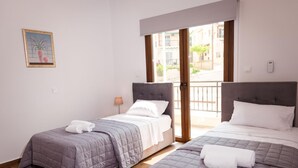 Una camera d'albergo con due letti, un balcone e un quadro appeso al muro.