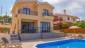 Un edificio a due piani con piscina, area salotto all'aperto e un balcone.