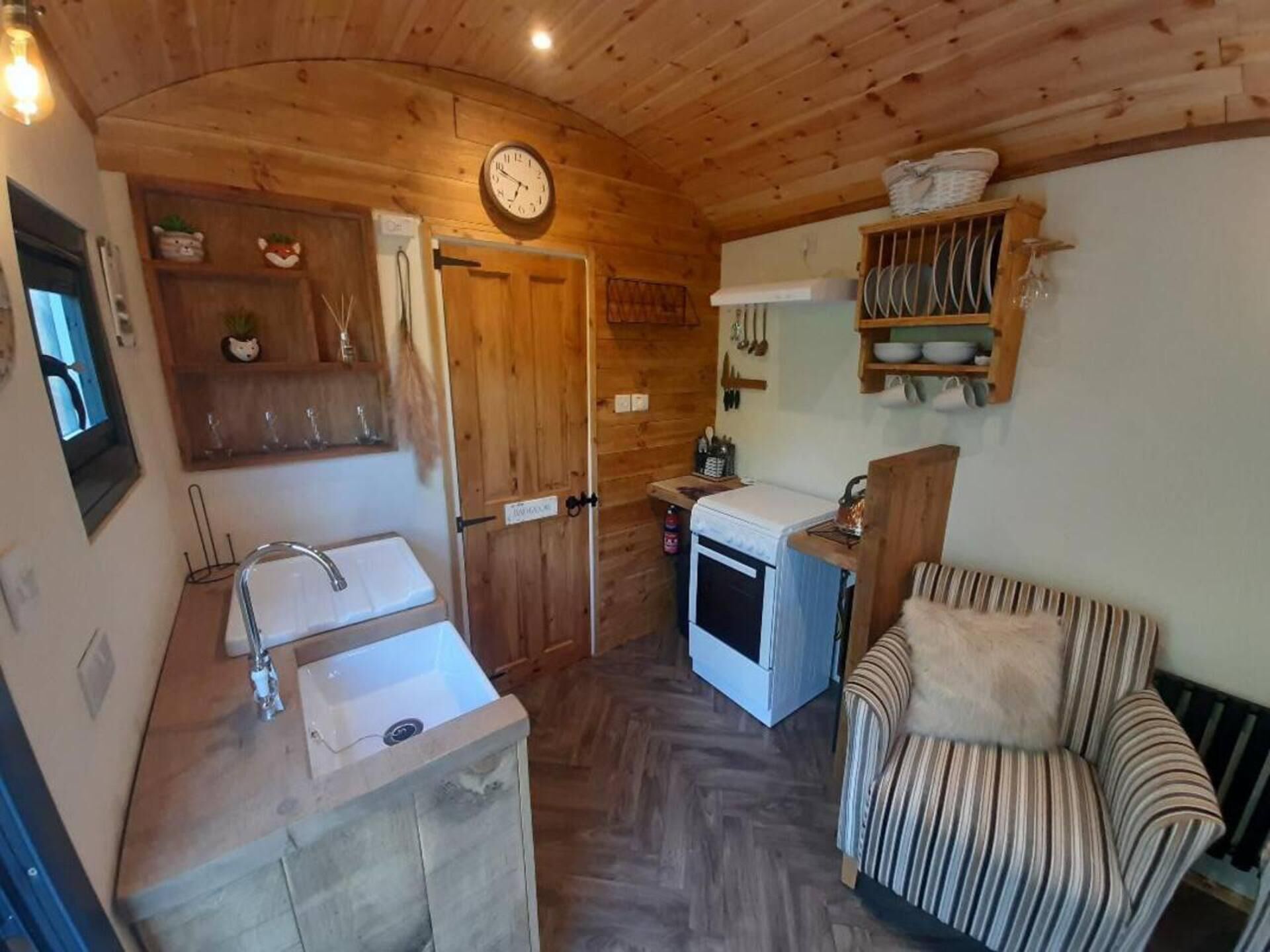 A cozy kitchen with wooden cabinets, a sink, a stove, and a chair.
