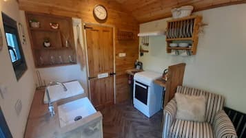 A cozy kitchen with wooden cabinets, a sink, a stove, and a chair.