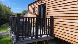 A wooden cabin with a black metal railing and a small window.