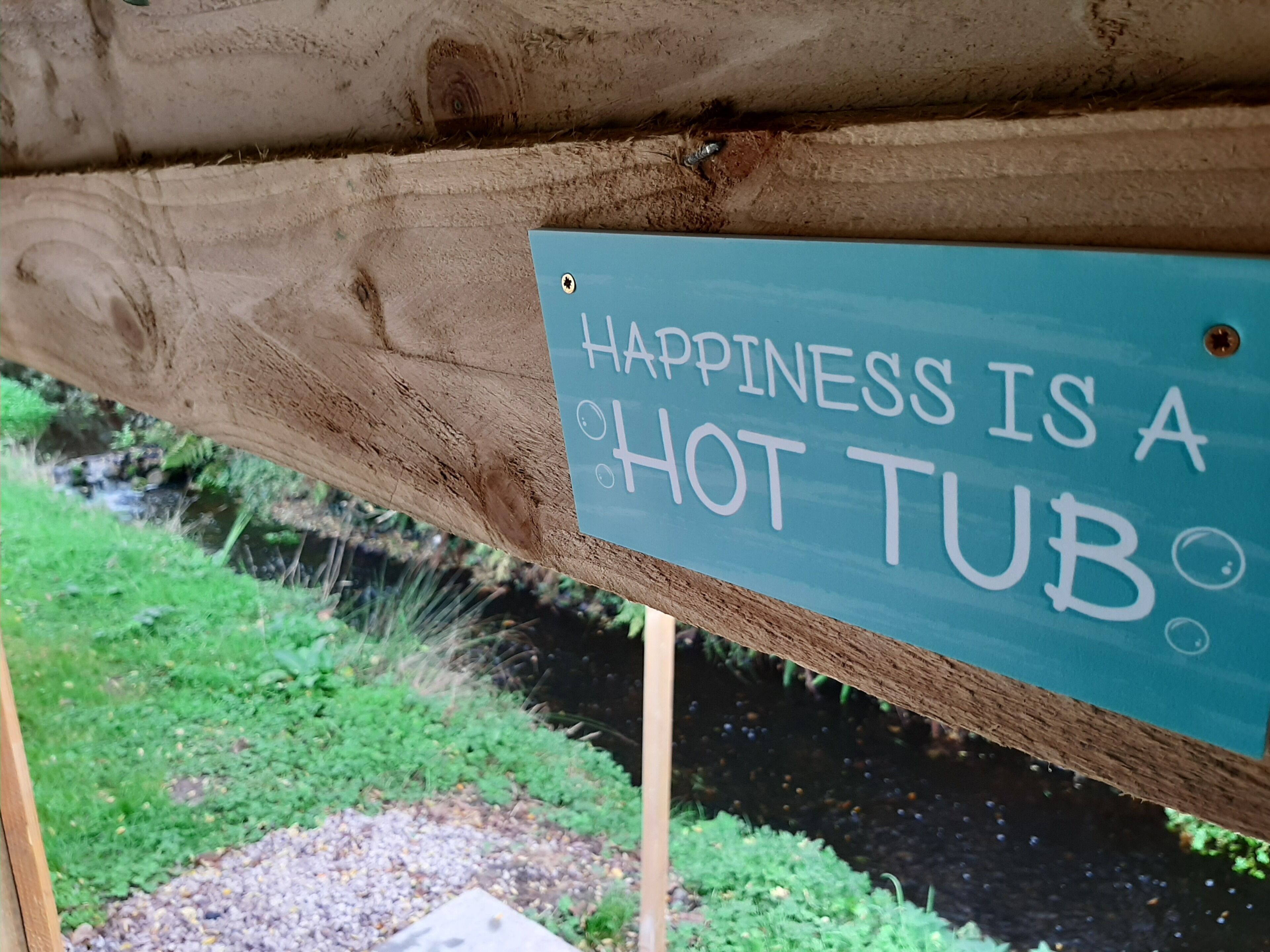 Una struttura in legno con un cartello che recita: 'Happiness is a hot tub'.