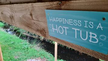 Una struttura in legno con un cartello che recita: 'Happiness is a hot tub'.