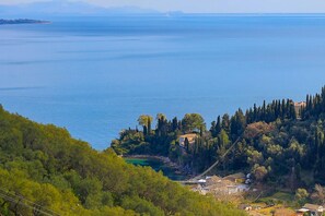 Escape to a serene coastal haven with breathtaking views of the expansive sea and lush green hills.