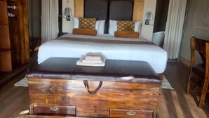 A bedroom with a large bed, wooden headboard, two bedside tables with lamps, and a wooden chest of drawers. - Tsabong Eco-Tourism Camel Park (Tshabong)