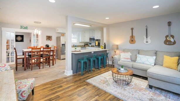 A modern living room with a sofa, a coffee table, and a dining area with chairs and a table. - Ivywood Escape Relaxing Stay (30+ Day Rental) (Nashville)