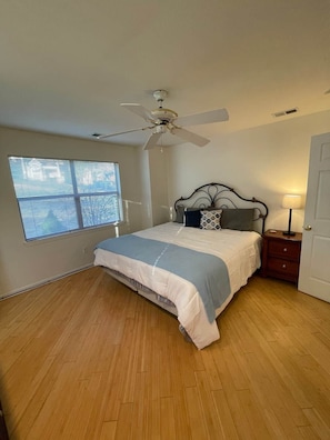 A bedroom with a bed, a ceiling fan, a window with blinds, a nightstand, and a door. - Awesome Pointe Royale Walk In (Branson)