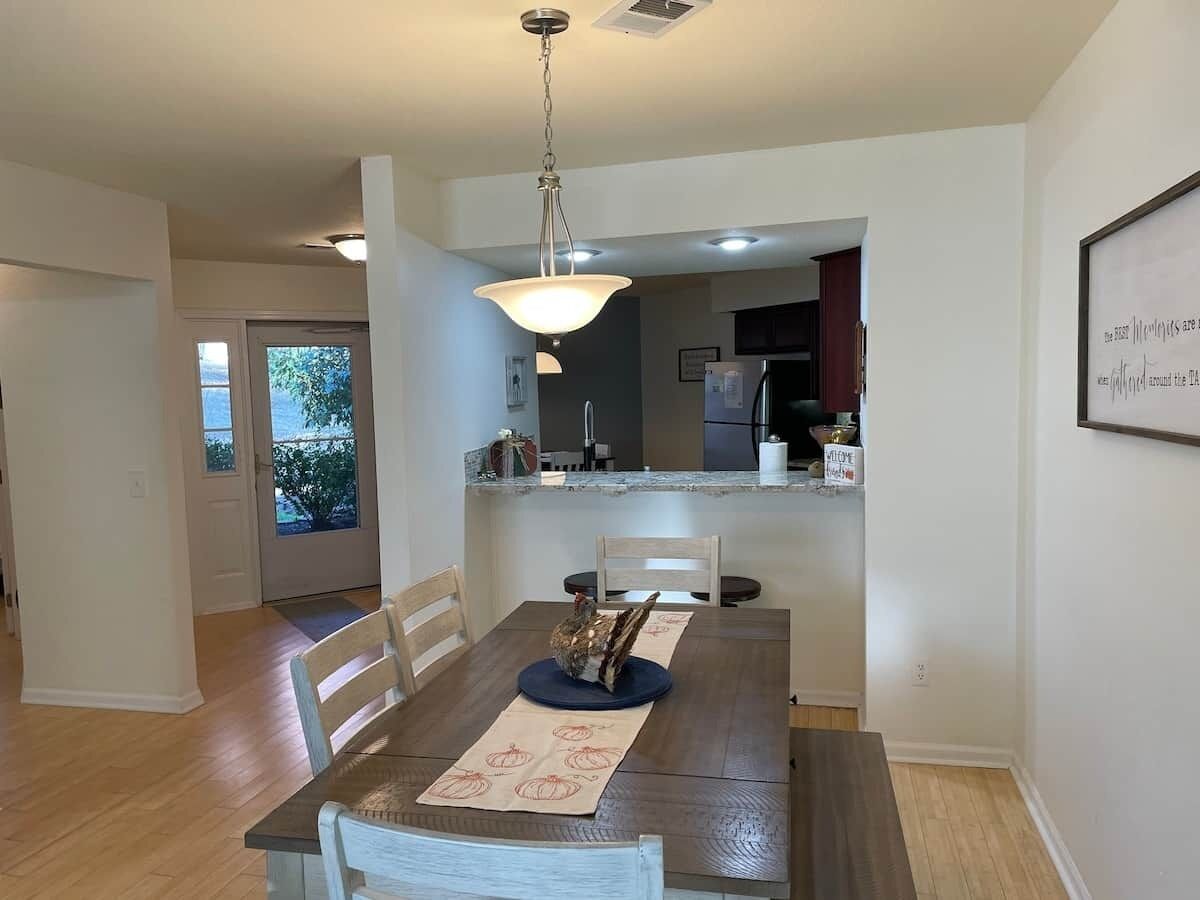 A dining area with a table, chairs, a decorative bird, and a kitchen in the background.