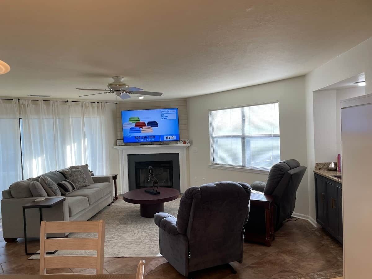 A living room with a sofa, chairs, a coffee table, a fireplace, and a television.