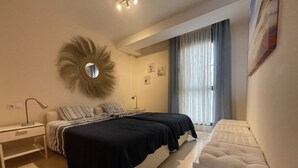 Een slaapkamer met twee bedden, een nachtkastje, een lamp, een spiegel en een raam met gordijnen.