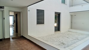 Een ruime kamer met een hoge plafond, een groot raam en een balkon.