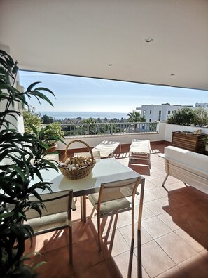 Eine Terrasse mit Tisch, Stühlen und einer Korb voller Snacks.