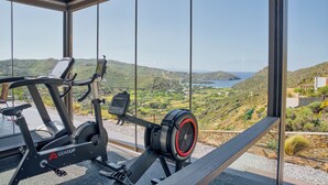 Un vélo d’appartement doté d’un écran numérique et offrant une vue sur un paysage côtier grâce à de grandes fenêtres.