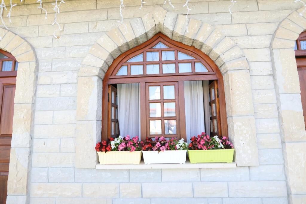 A stone building with a large arched window and flower boxes below.