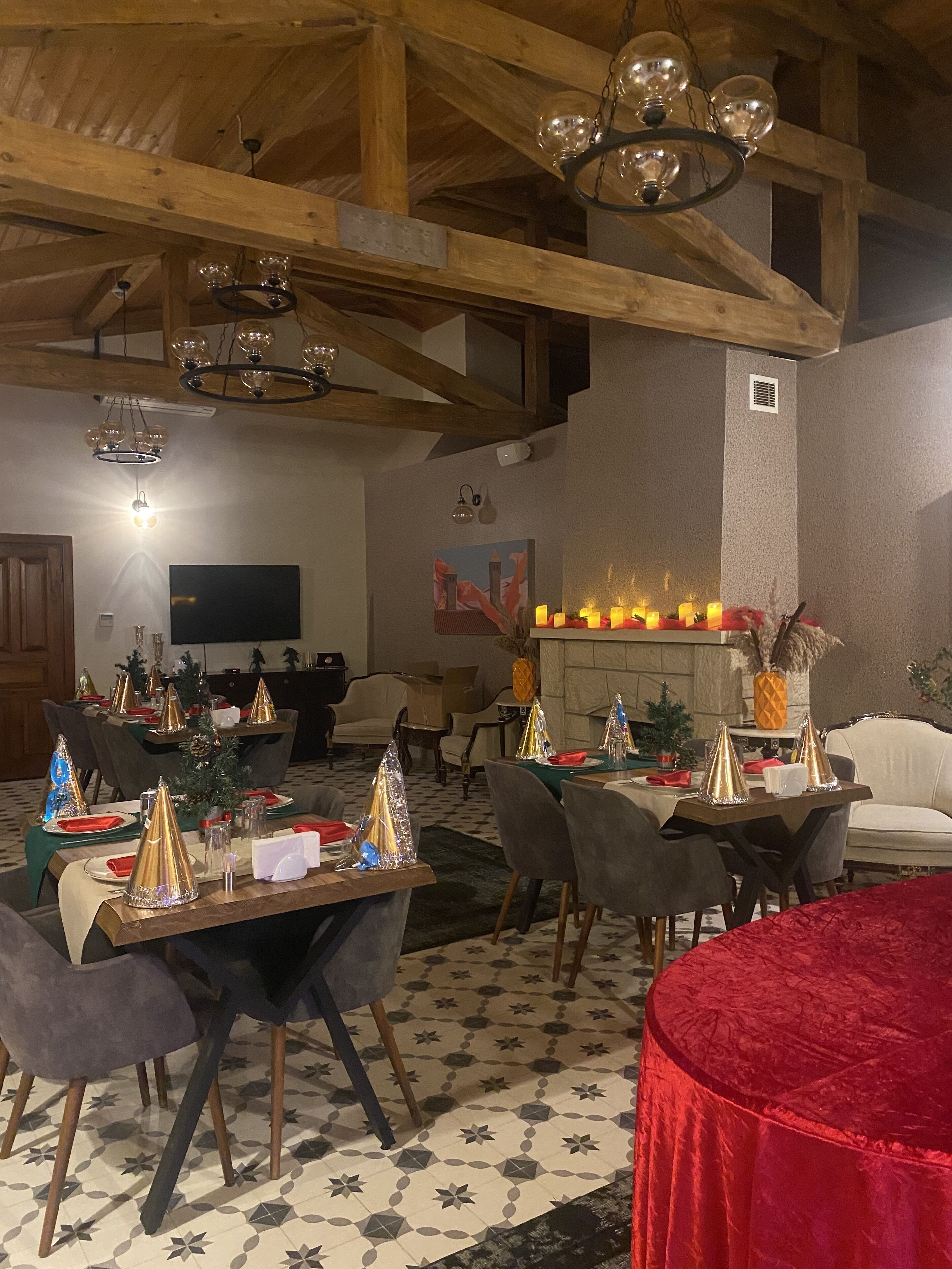Un comedor con mesas dispuestas para una comida, una chimenea con velas y una araña.
