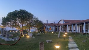A cemetery with a hammock, stone headstones, and a pathway leading to a building with a red roof. - Tarihi Kumbaba Otel (Sile)