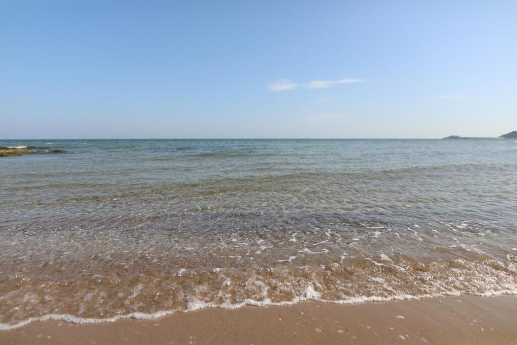 A beach with clear water and a sandy shore.