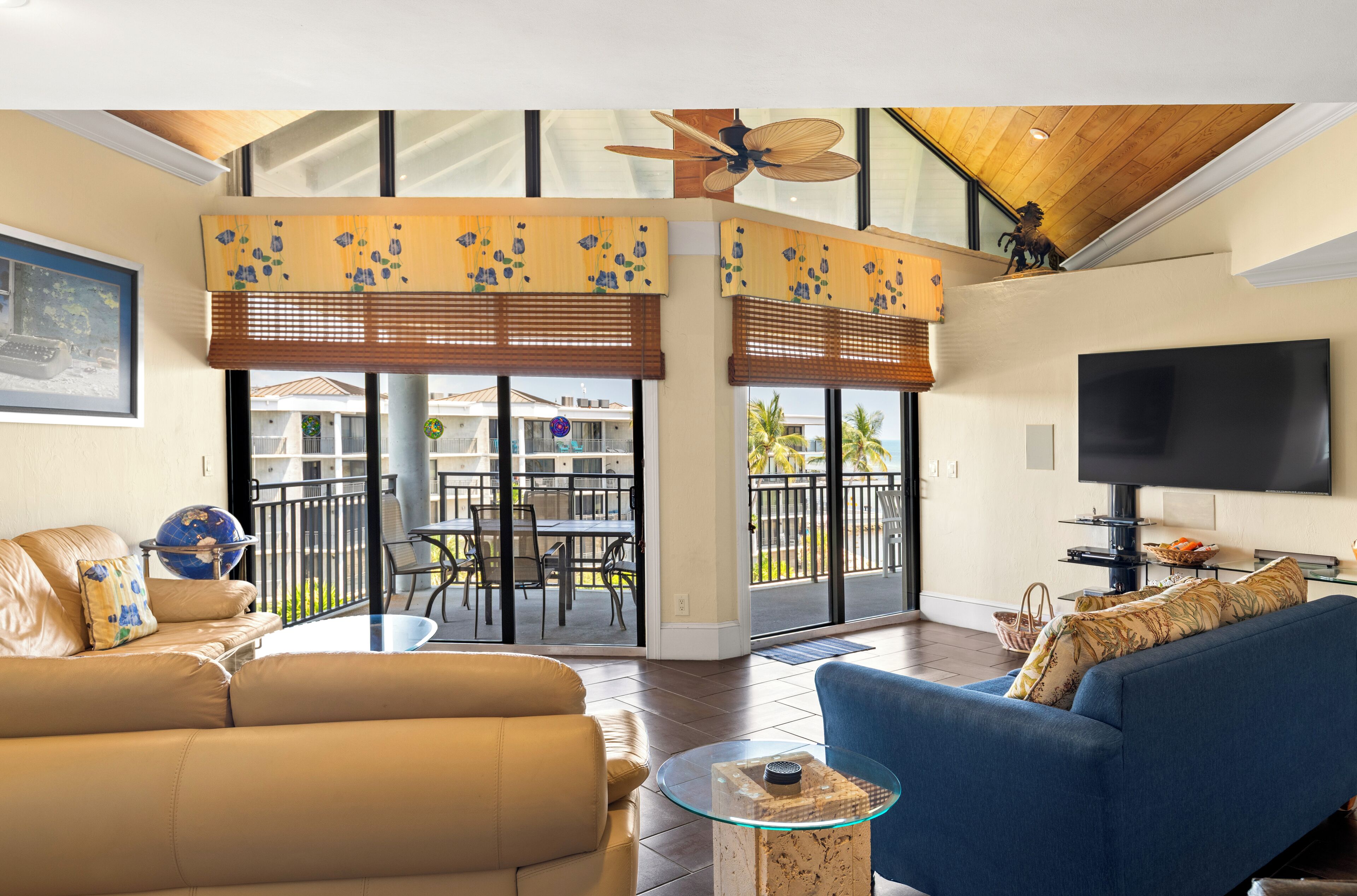 Una sala de estar con sofá, mesa de centro, televisor y balcón con vistas al exterior.