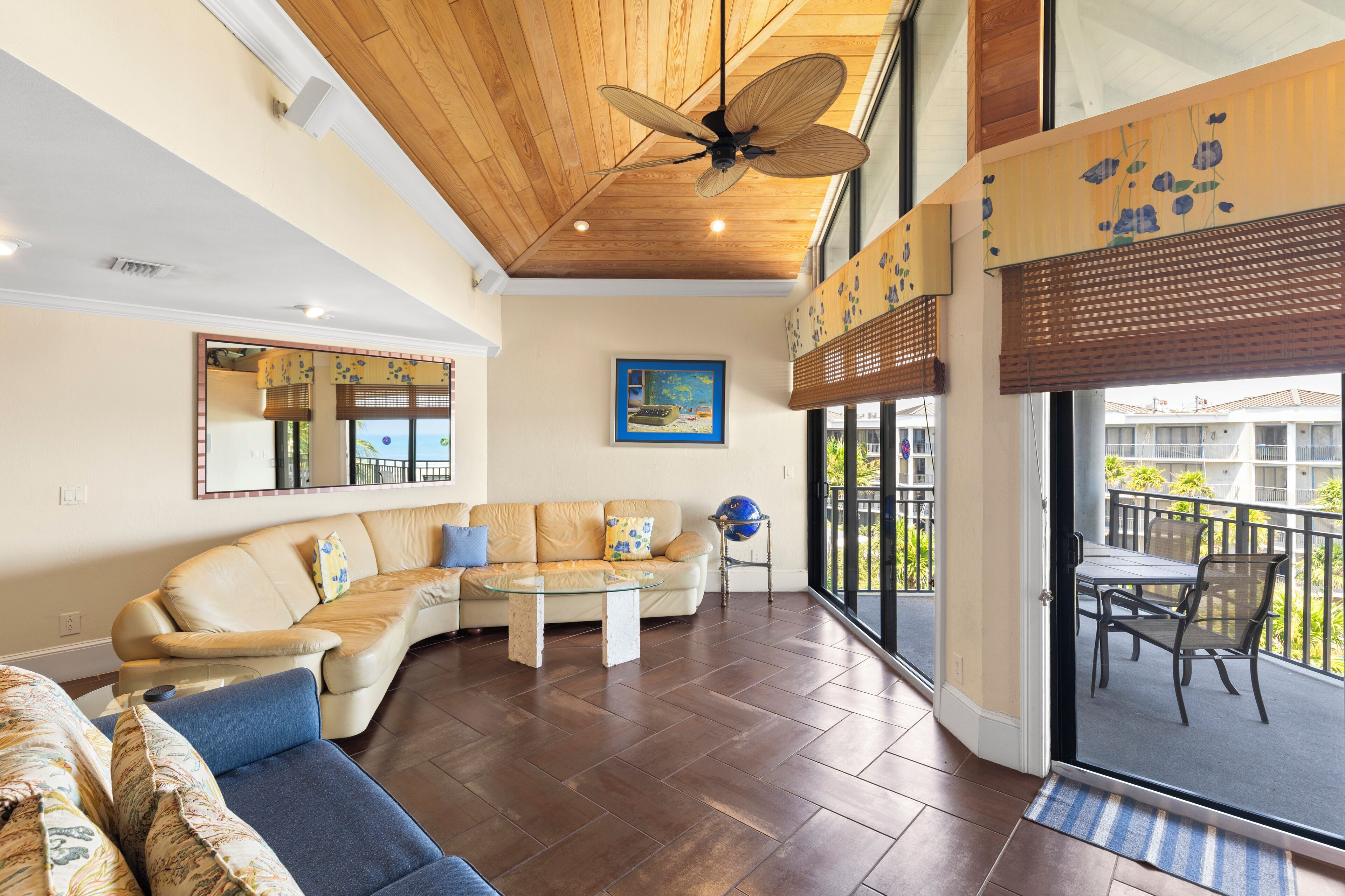 Un vaste espace de vie doté d’un plafond en bois, d’une grande fenêtre et d’un balcon aménagé avec du mobilier d’extérieur.