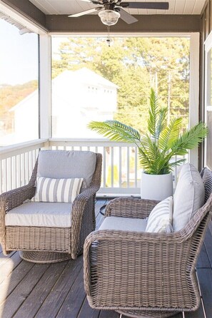 A covered porch with wicker furniture, a ceiling fan, and a potted plant.