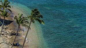 A beach with clear turquoise water, palm trees, and rocky shoreline. - Oceanfront Maui condo w/ lanai and pool access (Lahaina)