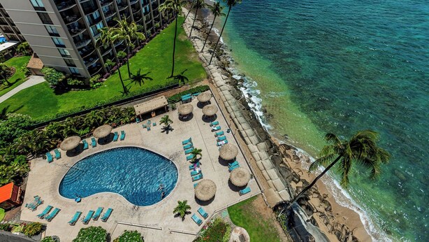 A resort with a large swimming pool, sun loungers, and a view of the ocean. - Oceanfront Maui condo w/ lanai and pool access (Lahaina)