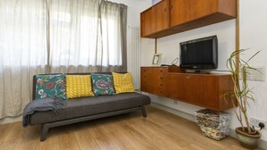 A living room with a sofa, television, wooden cabinet, and a potted plant. - Stylish 1BR Next to Tower Bridge (London)