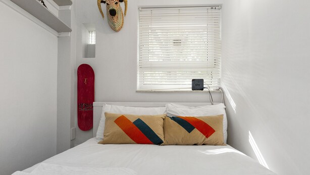 A neatly made bed with white linens and two pillows with geometric patterns. - Stylish 1BR Next to Tower Bridge (London)