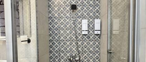Una ducha con pared de azulejos con diseño, puerta de cristal y suelo de madera.