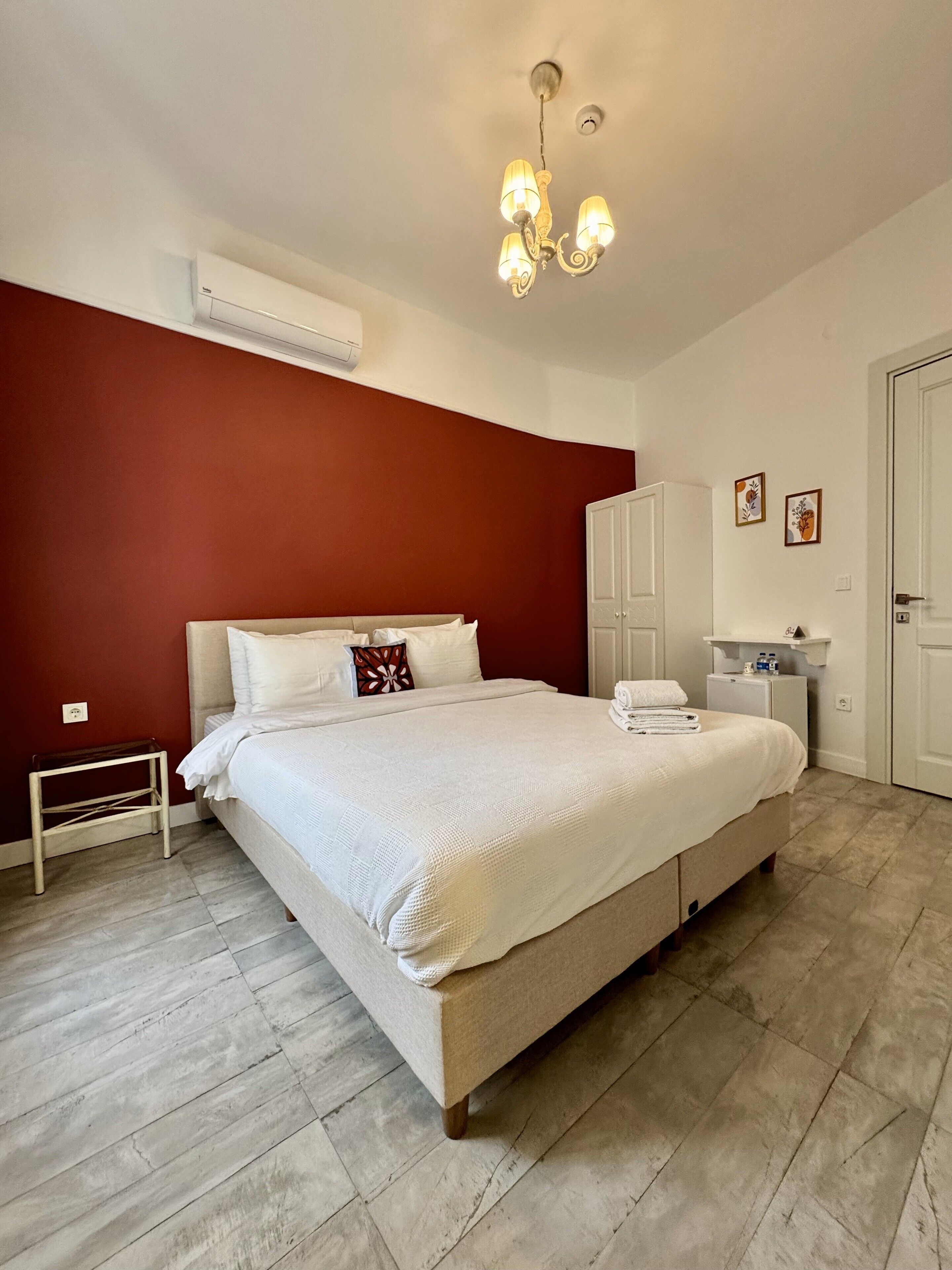 Une chambre à coucher comprenant un lit, une table de chevet, une armoire et un lustre.