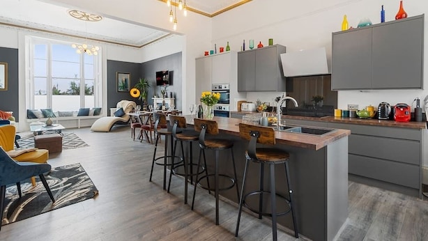 Une cuisine moderne dotée d’un îlot central, de tabourets de bar et d’un coin repas comprenant un canapé et une table basse.