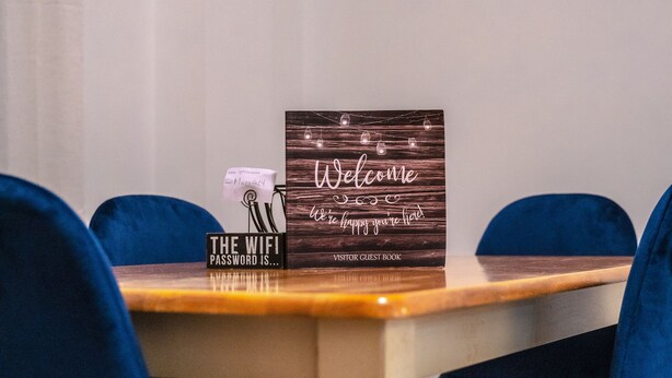 A wooden table with a sign that reads "Welcome, we're happy you're here" and a sign that says "The WiFi password is...".