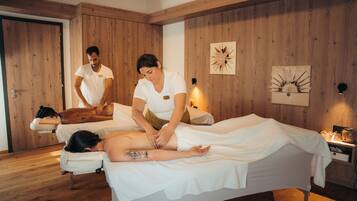 Et massageværelse med trævægge, en massagestol og et lille natbord med lampe.