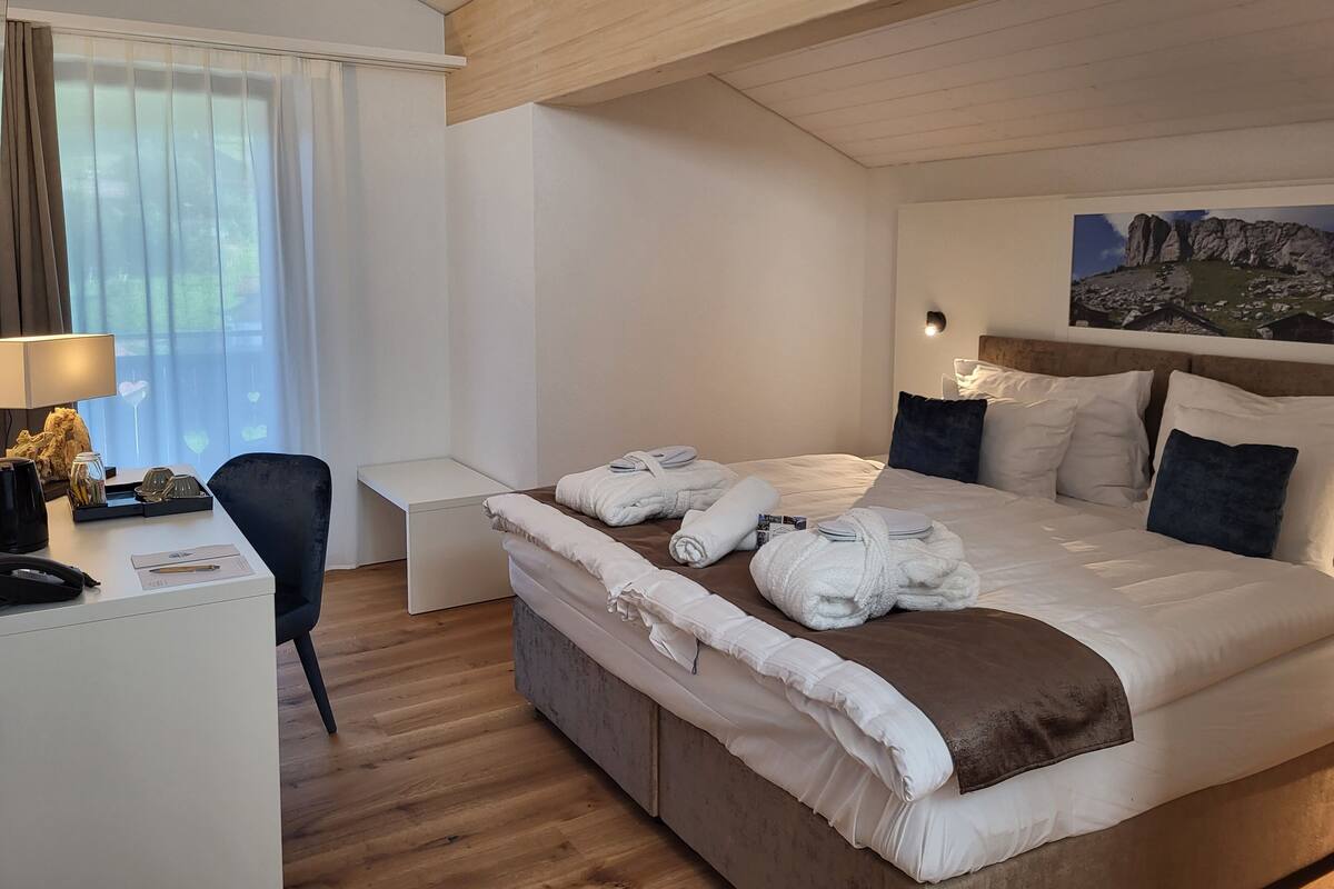 A hotel room with a bed, bedside tables, a desk, and a chair.