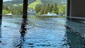 An indoor swimming pool with a view of a mountainous landscape through large windows. - Boutique Hôtel Corbetta (Chatel-Saint-Denis)