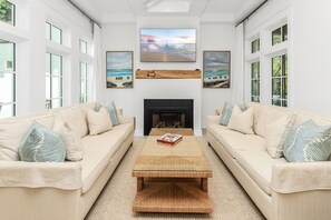 A spacious living room with two beige sofas, a central coffee table, and a fireplace.