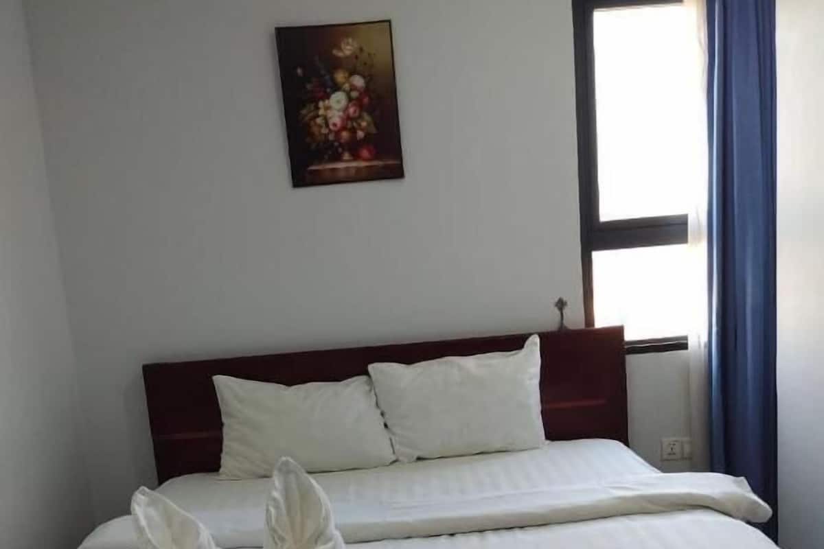 A neatly made bed with white linens and two towels placed on the bed.