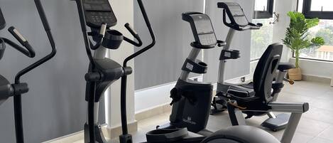 Un gimnasio con bicicletas estáticas, cintas de correr y una máquina de remo.