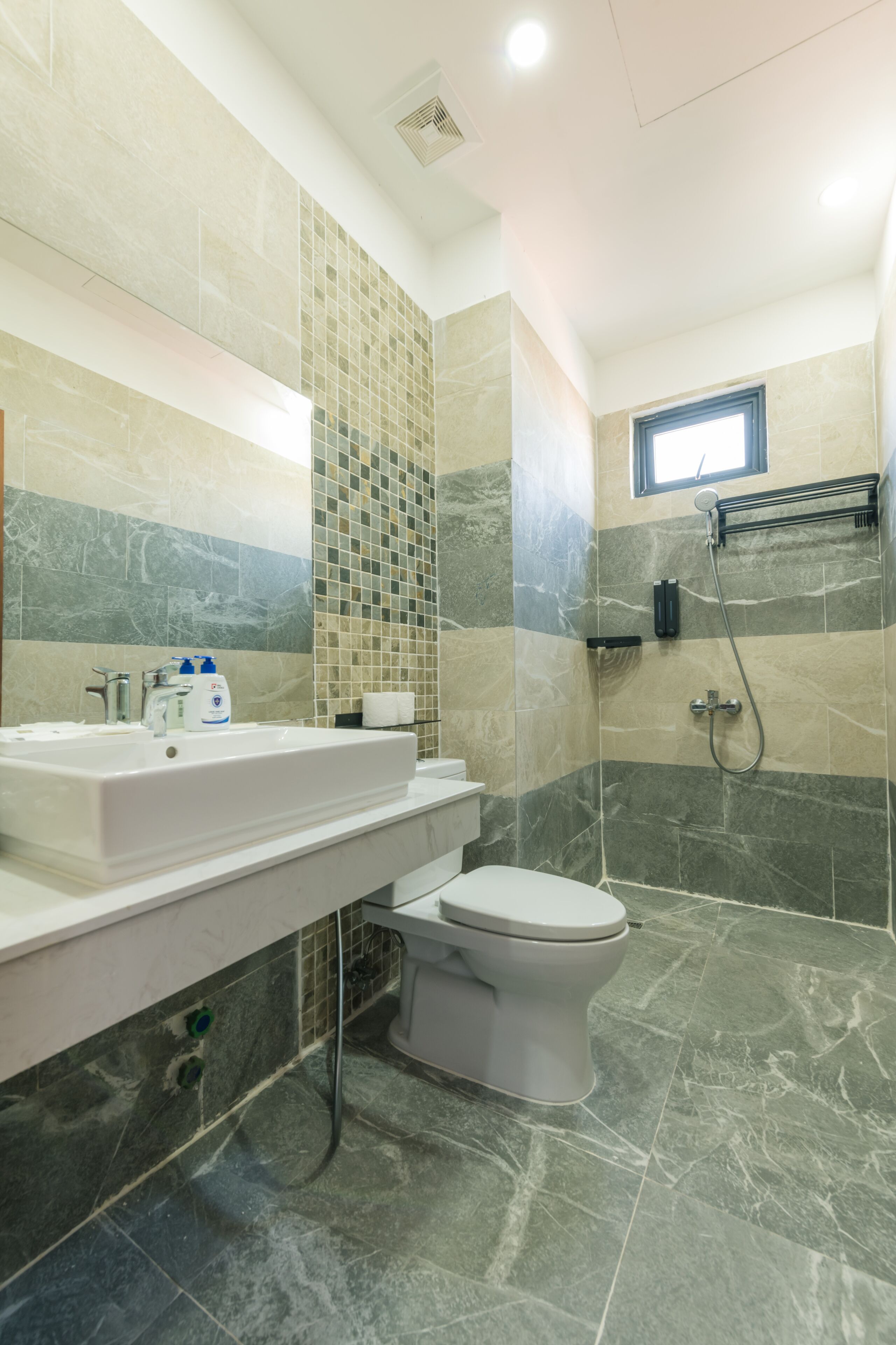 Un baño moderno con lavamanos, inodoro y ducha blancos.
