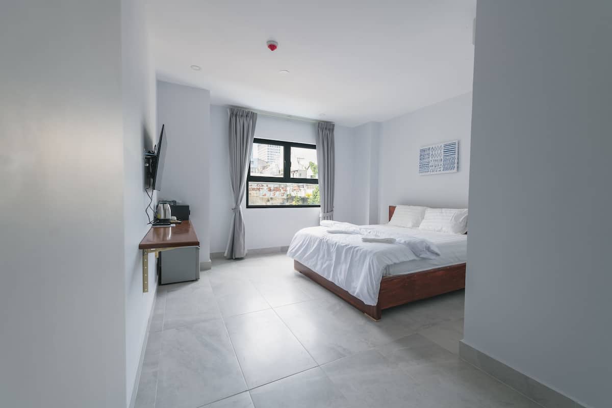 A modern bedroom with a bed, a desk, and a window.