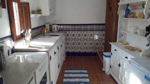 Une cuisine avec des meubles blancs, un pare-feu en carreaux et un tapis à rayures.