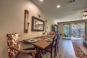 Uma sala de jantar com mesa de madeira, cadeiras e vista para o exterior.