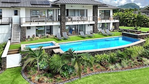 Ein zweistöckiges Haus mit Pool, Balkon und Bergblick.