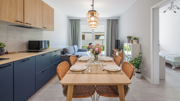 Een moderne keuken met houten kasten, een eettafel voor zes personen en uitzicht op de woonkamer.