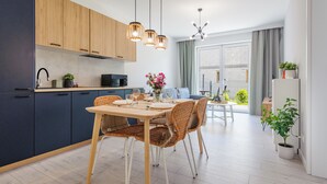 Een moderne keuken met donkere kastjes, een magnetron, en een eethoek met rieten stoelen en een tafel gedekt voor twee personen.